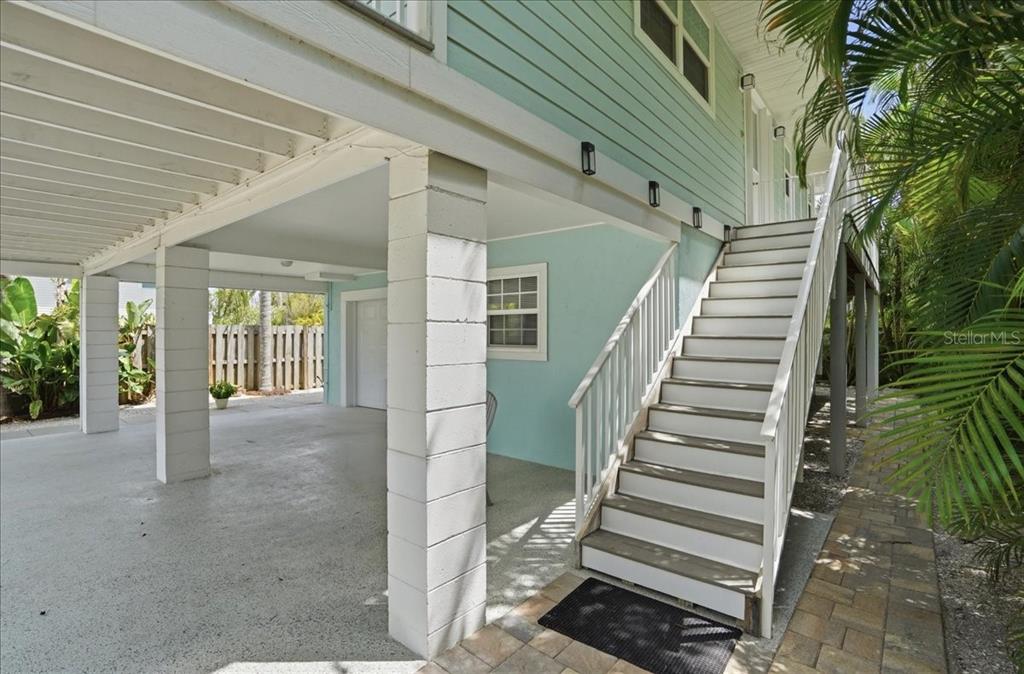 An elevated house with light blue siding, a concrete carport, and a white staircase — 2811 GULF DRIVE, HOLMES BEACH, FL