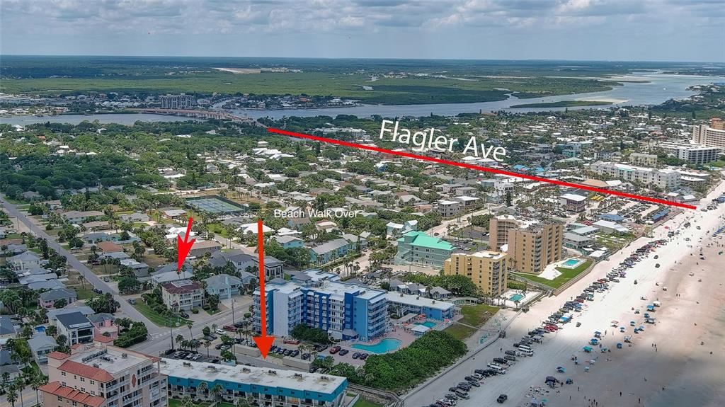 An aerial view shows a coastal town with a beach, multi-story buildings, and marked streets — 818 OCEAN AVENUE, NEW SMYRNA BEACH, FL