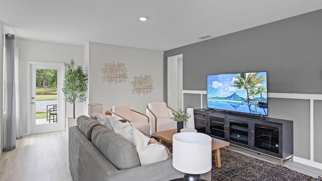 A living room features a gray sofa, two cream armchairs, and a television on a console — 4053 GIORGIO DRIVE, WINTER HAVEN, FL