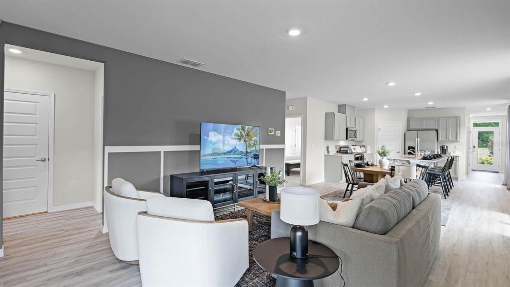 A living room features a gray accent wall, white wainscoting, and an open-concept kitchen — 4053 GIORGIO DRIVE, WINTER HAVEN, FL
