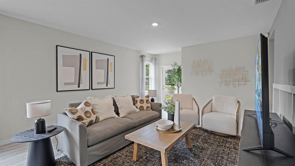 A living room features a grey sofa, two white armchairs, a coffee table, and wall art — 4053 GIORGIO DRIVE, WINTER HAVEN, FL