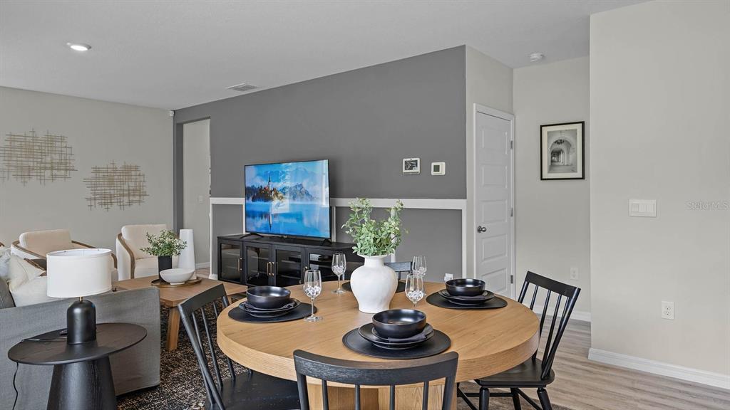 A dining area with a round wooden table sits in front of a gray accent wall — 4053 GIORGIO DRIVE, WINTER HAVEN, FL