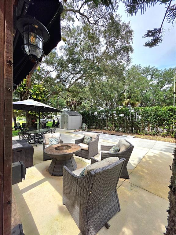 A patio features four wicker chairs surrounding a round fire pit table under a pergola — 159 HORSESHOE BEND, LAKE WALES, FL