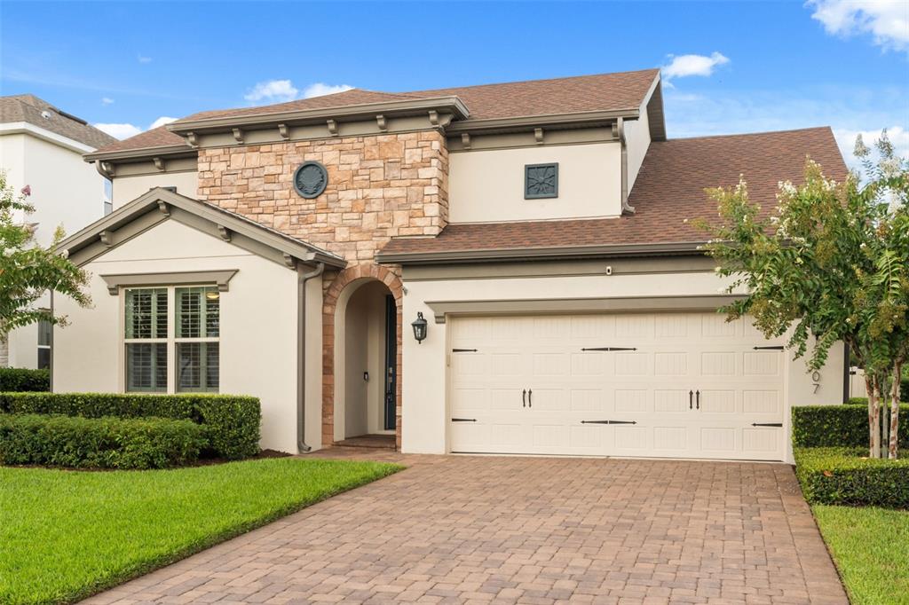 A two-story house with a stone facade, stucco walls, and a paved driveway — 17307 BAL HARBOUR DRIVE, WINTER GARDEN, FL