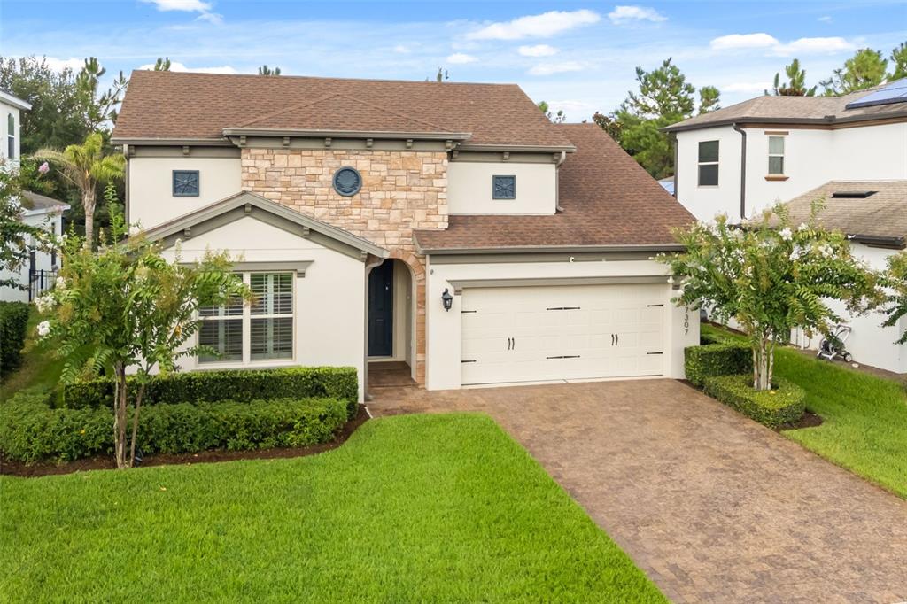 A two-story suburban house features a stone-accented facade, a two-car garage, and a paved driveway — 17307 BAL HARBOUR DRIVE, WINTER GARDEN, FL