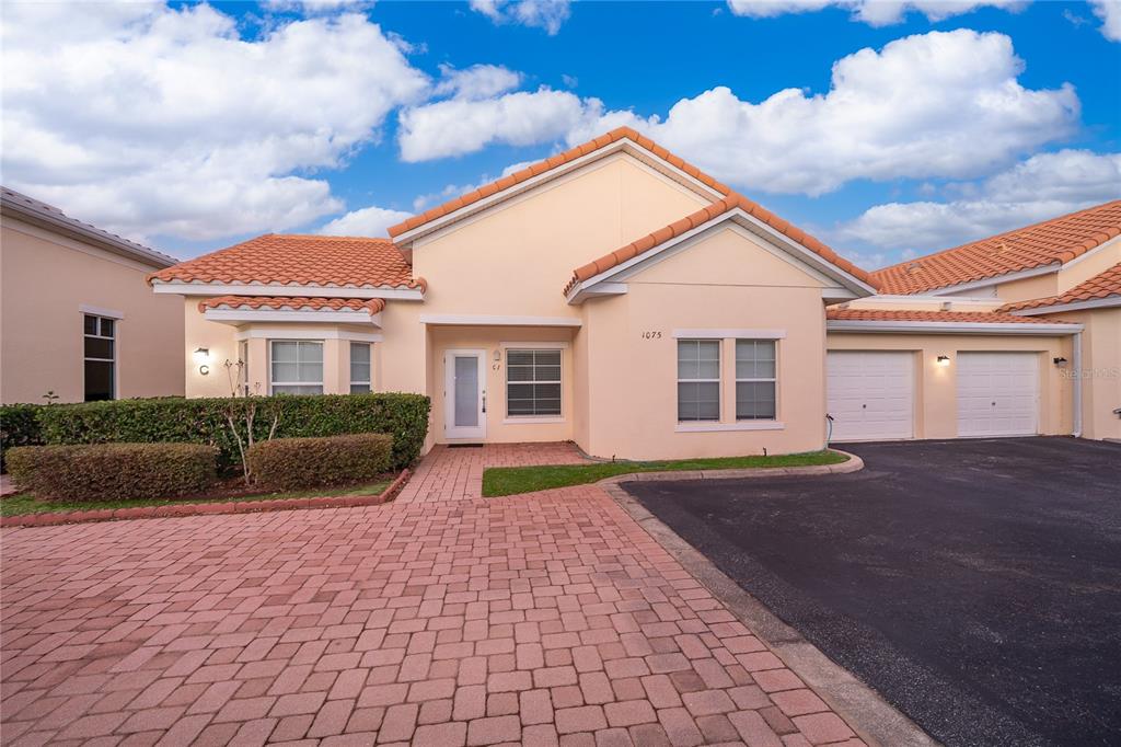 A single-story house with a peach stucco exterior, tile roof, and a brick paver driveway — 1075 DAVID WALKER DRIVE UNIT C-1, TAVARES, FL