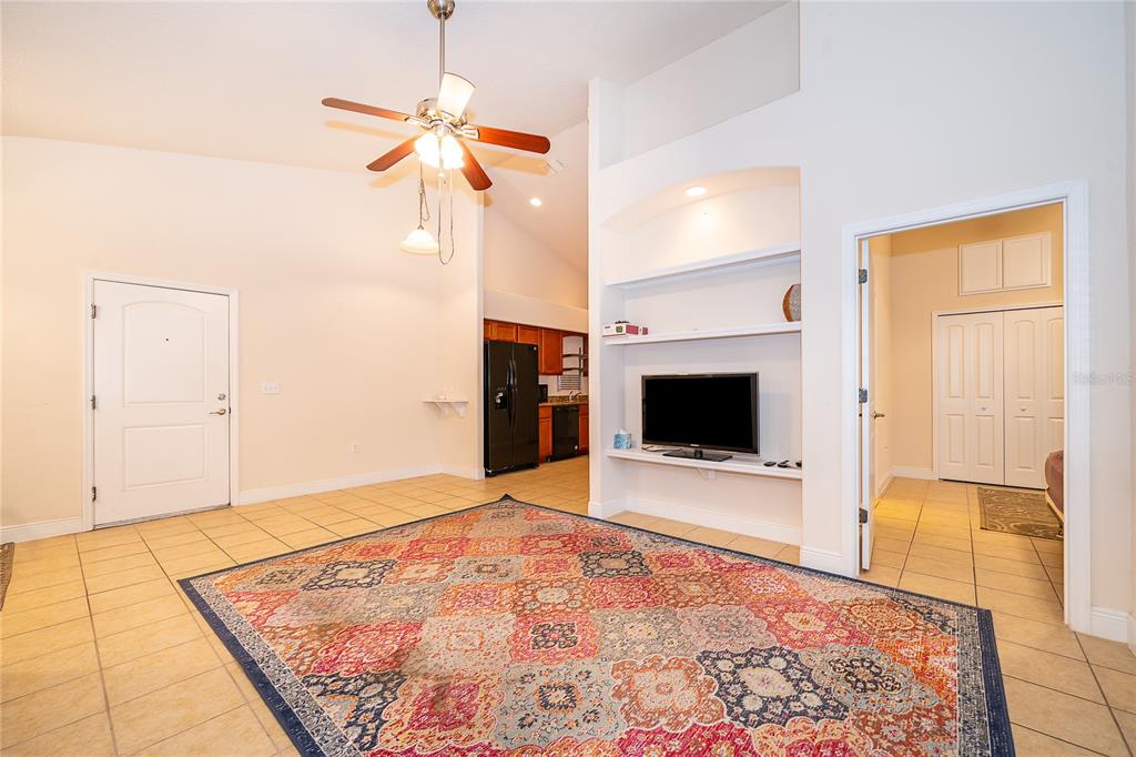 A living room with tile flooring, a ceiling fan, and a built-in media niche — 1075 DAVID WALKER DRIVE UNIT C-1, TAVARES, FL