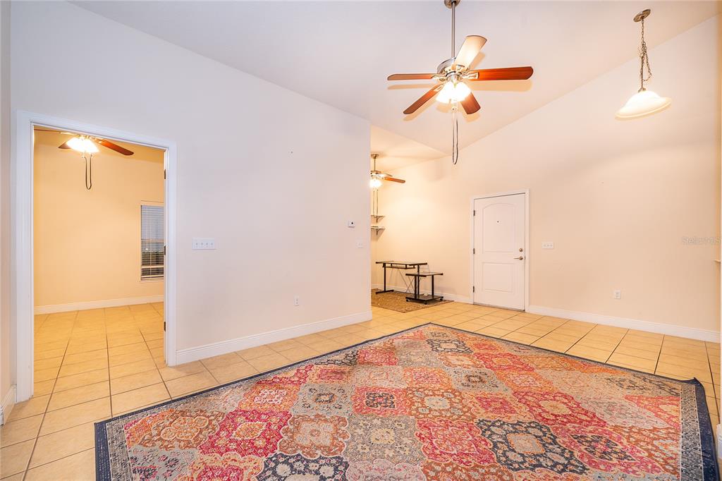 A living room with tile floors, a ceiling fan, and a large patterned area rug — 1075 DAVID WALKER DRIVE UNIT C-1, TAVARES, FL