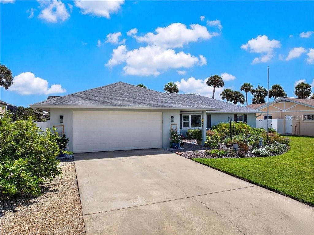 A single-story house with a white garage door, a concrete driveway, and a landscaped front yard — 263 OCEAN PALM DRIVE, FLAGLER BEACH, FL