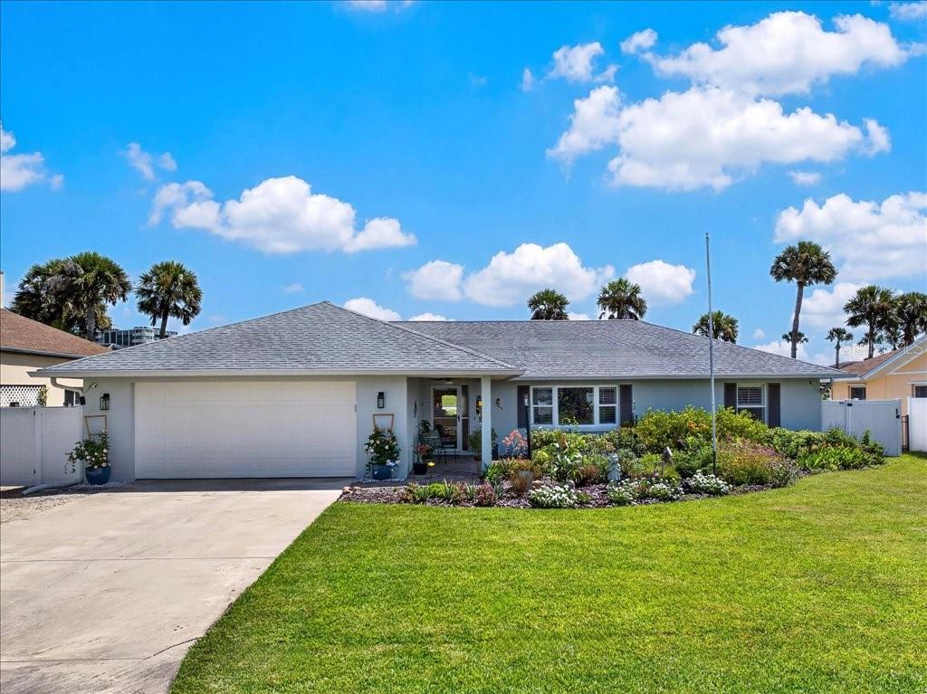 A single-story house with a gray roof, white garage door, and a landscaped front yard — 263 OCEAN PALM DRIVE, FLAGLER BEACH, FL