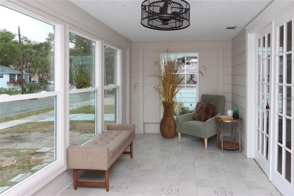 A sunroom with gray tile flooring, a tufted bench, an armchair, and a ceiling fan — 1532 13TH STREET S, ST PETERSBURG, FL