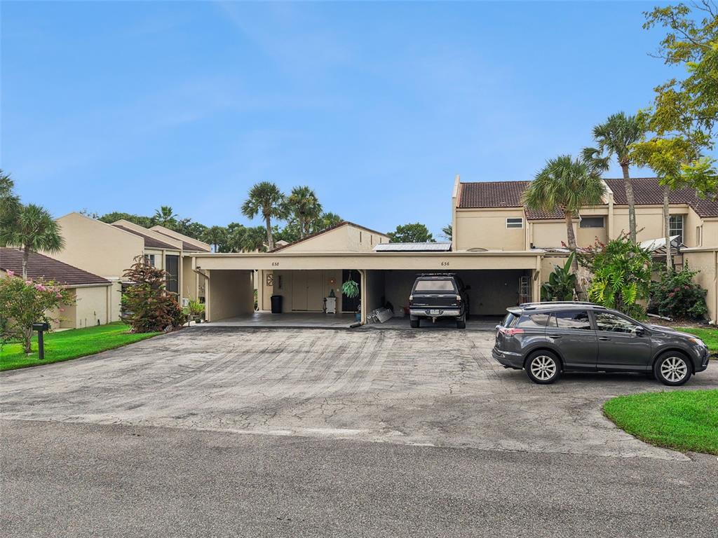 A beige residential building features a shared carport with two parking spaces and a driveway — 638 SAUSALITO BOULEVARD UNIT B5, CASSELBERRY, FL