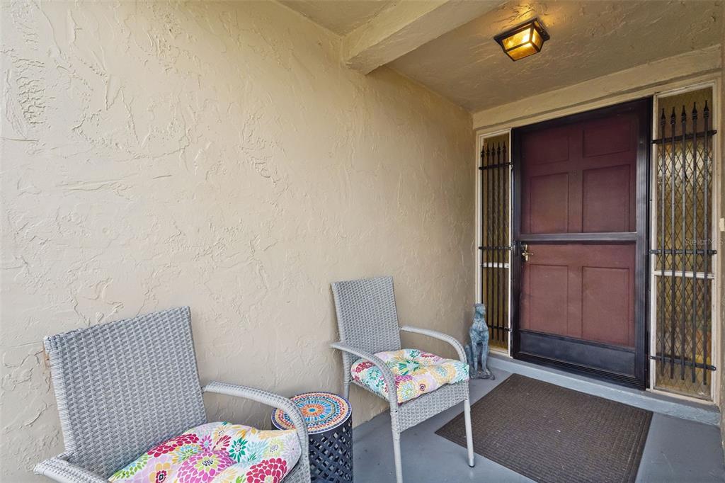 A covered entryway features two wicker chairs, a small side table, and a dark door — 638 SAUSALITO BOULEVARD UNIT B5, CASSELBERRY, FL