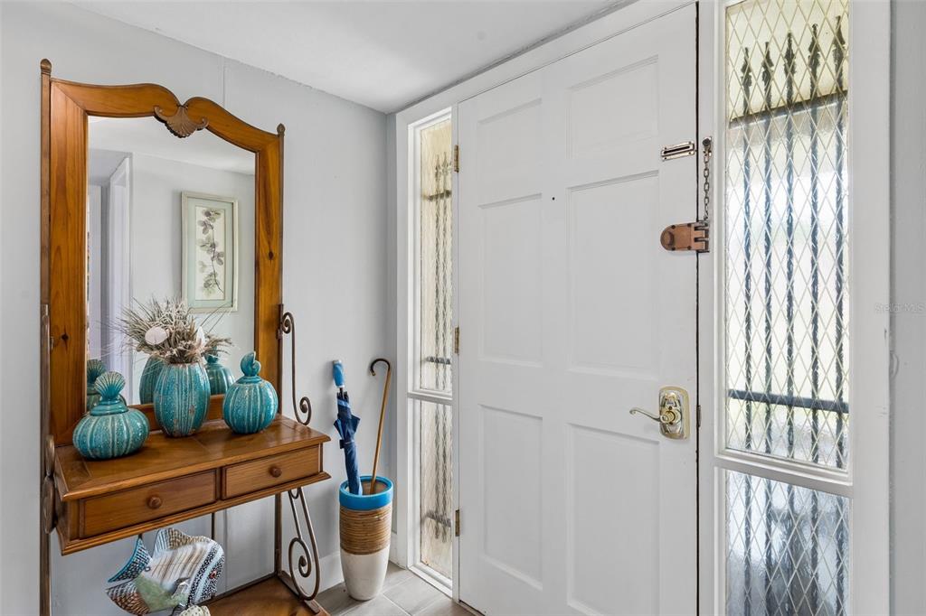 An entryway features a wooden console table with a mirror, an umbrella stand, and a door — 638 SAUSALITO BOULEVARD UNIT B5, CASSELBERRY, FL