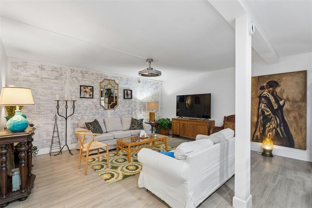 A living room features a white brick accent wall, light wood-look flooring, and two sofas — 638 SAUSALITO BOULEVARD UNIT B5, CASSELBERRY, FL