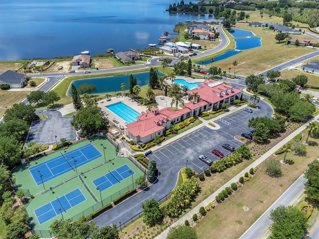 A swimming pool sits in front of a clubhouse with a red metal roof — 171 BLAZING STAR AVENUE, LAKE ALFRED, FL