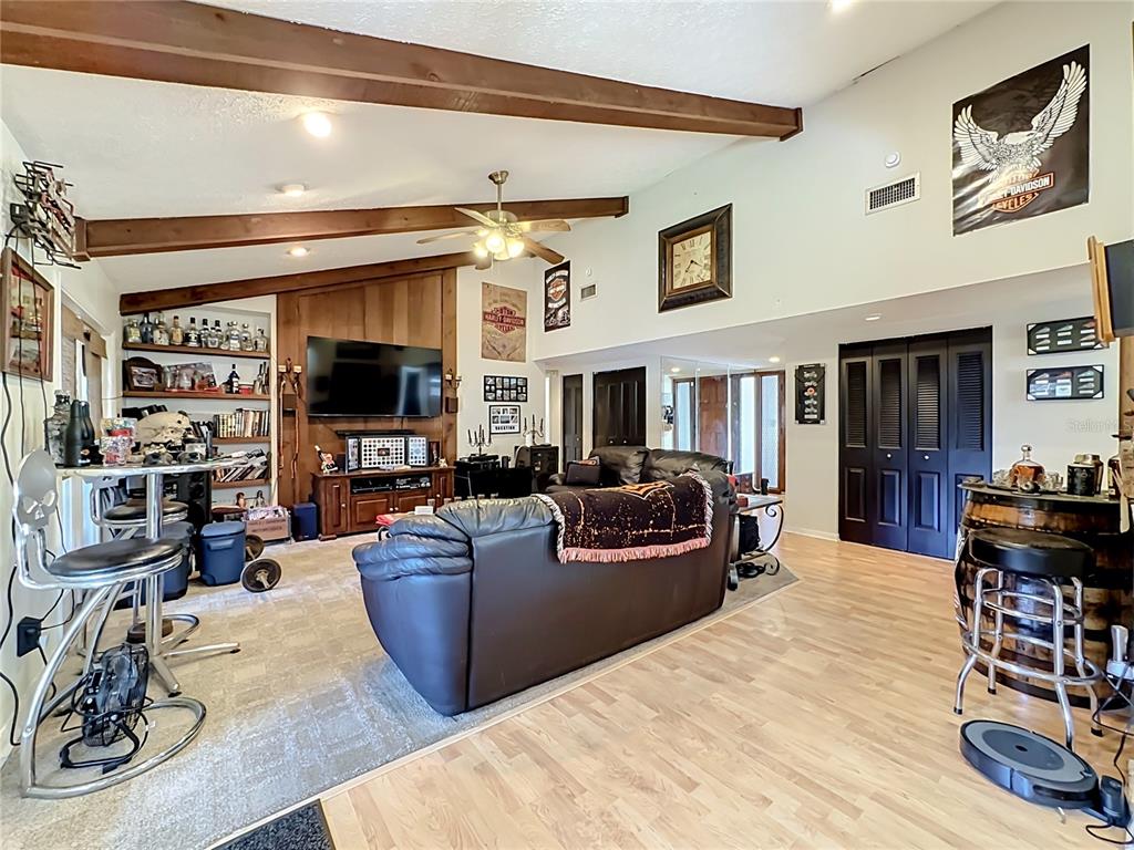 A living room features vaulted ceilings with exposed wood beams, a television, and bar seating — 118 EUCLID LOOP, SEFFNER, FL