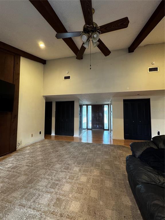 A hallway with wood flooring leads into a living room featuring vaulted ceilings and mirrors — 118 EUCLID LOOP, SEFFNER, FL