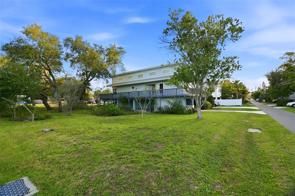 A two-story house with a large wooden deck stands on a grassy lot with trees — 0 GEORGIA AVE. AVENUE, CRYSTAL BEACH, FL