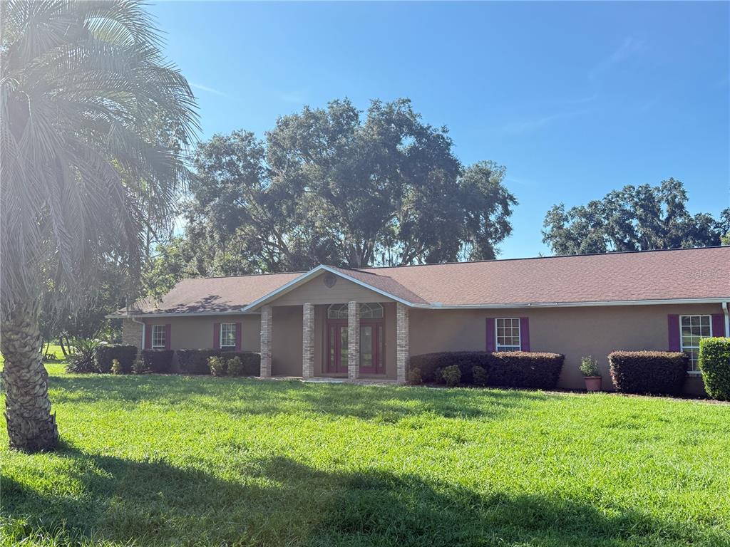 A single-story house with a tan exterior, brown roof, and a central covered entryway — 7613 NW 46TH STREET, OCALA, FL