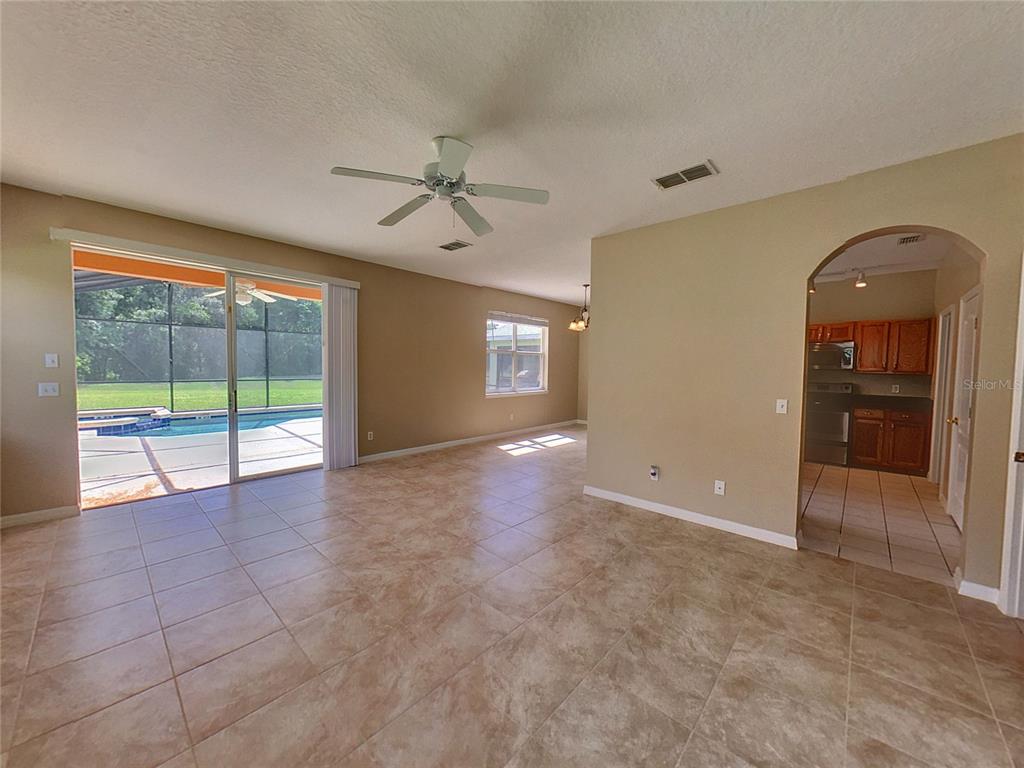 A spacious living area with tile floors, a ceiling fan, and sliding doors to a pool — 124 HAMMOCK COURT, DAVENPORT, FL