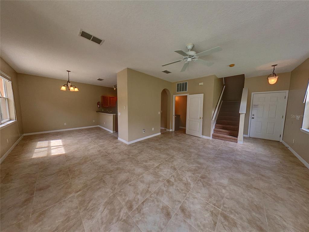 An open-concept living and dining area features tile flooring, a staircase, and a kitchen pass-through — 124 HAMMOCK COURT, DAVENPORT, FL