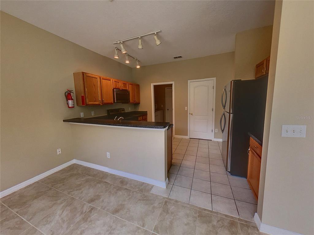 A kitchen with wood cabinets, a breakfast bar, and tile flooring — 124 HAMMOCK COURT, DAVENPORT, FL