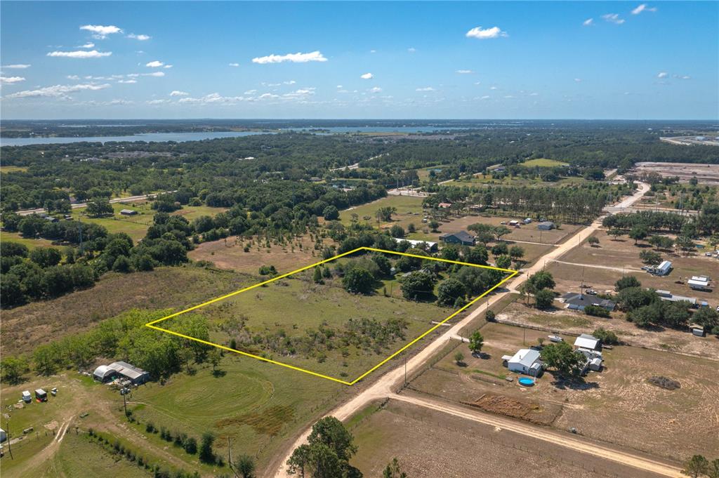 An aerial view shows a rectangular plot of land outlined in yellow near a road — 256 SUNRIDGE DRIVE, AUBURNDALE, FL