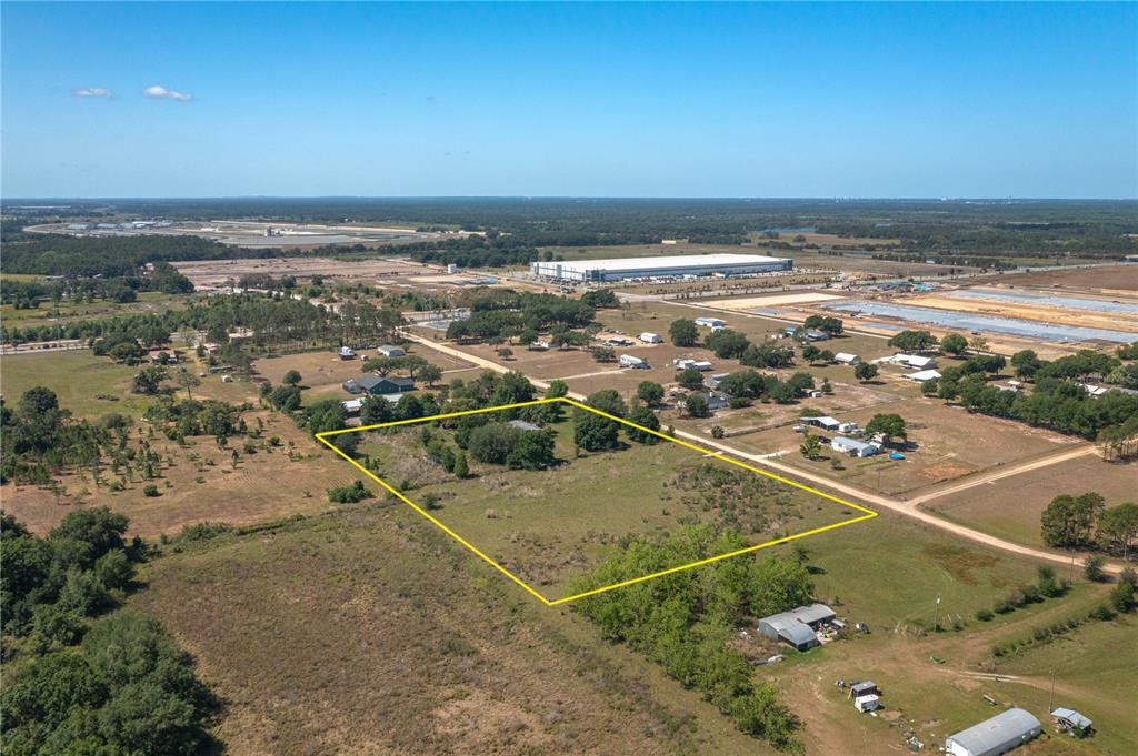 An aerial view shows a rectangular plot of land outlined in yellow with scattered trees — 256 SUNRIDGE DRIVE, AUBURNDALE, FL