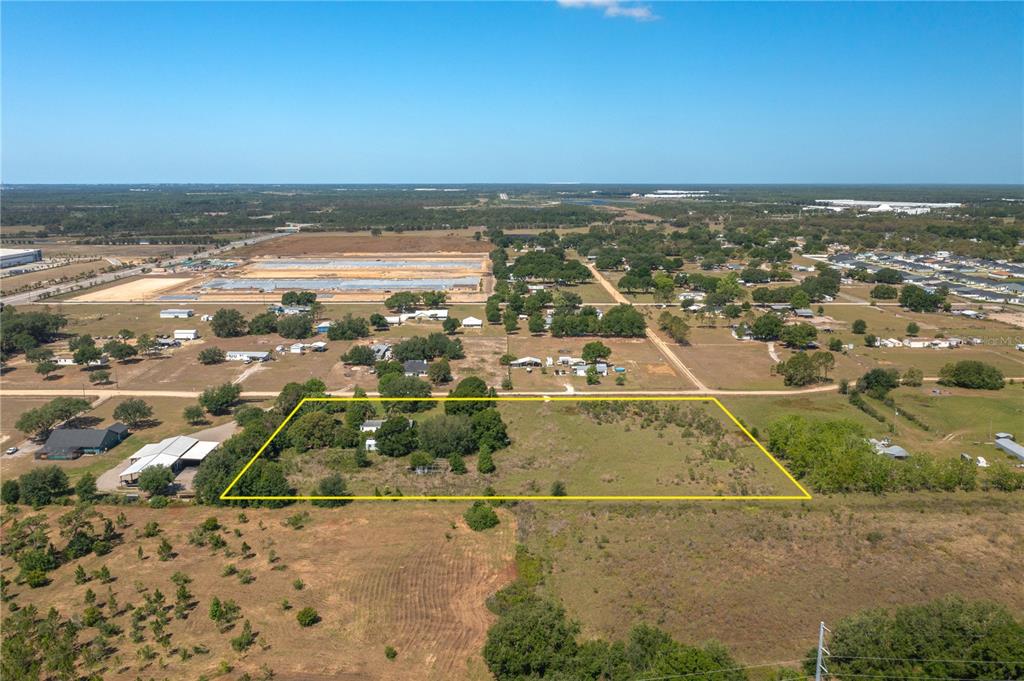 An aerial view shows a rectangular plot of land outlined in yellow with a house — 256 SUNRIDGE DRIVE, AUBURNDALE, FL