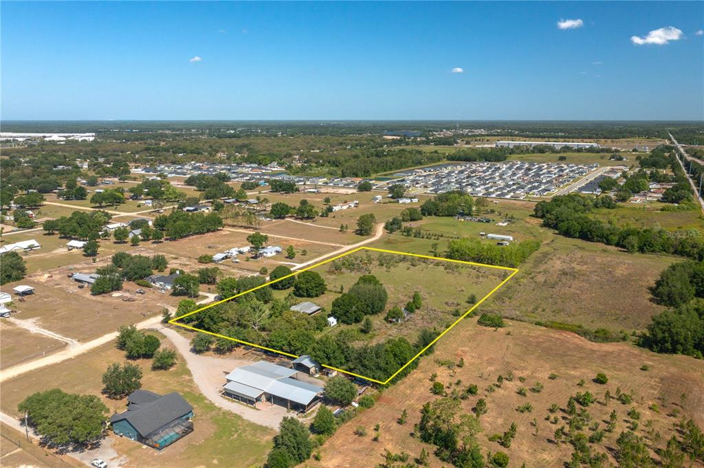 An aerial view shows a rectangular plot of land outlined in yellow with several structures — 256 SUNRIDGE DRIVE, AUBURNDALE, FL