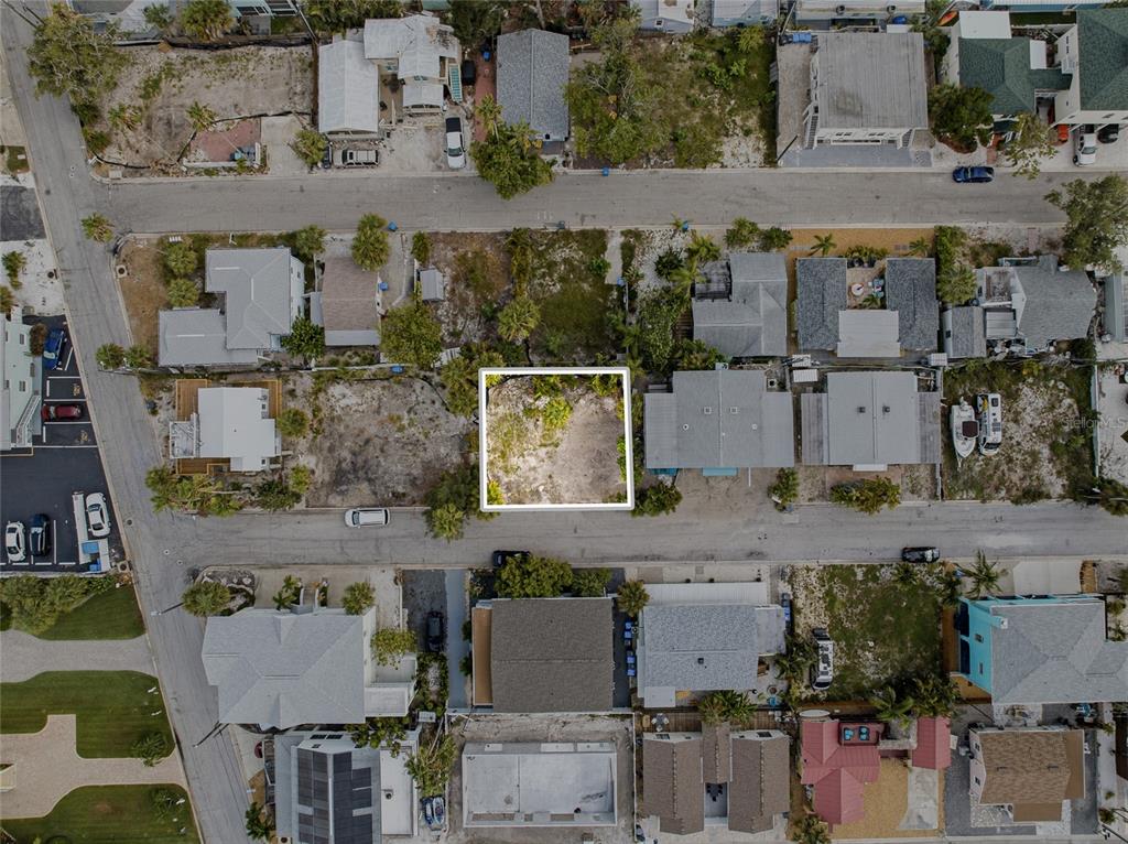 An aerial view shows a vacant, rectangular residential lot outlined in white between existing houses — 131 86TH TERRACE, TREASURE ISLAND, FL