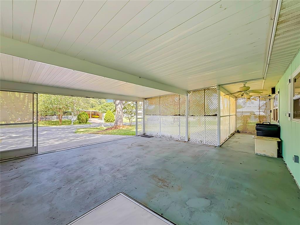 A covered concrete patio features white lattice walls, a ceiling fan, and a screen enclosure — 10035 SW 91ST TERRACE, OCALA, FL