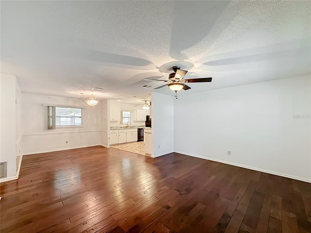 A living room with dark hardwood floors, a ceiling fan, and an adjacent white kitchen — 10035 SW 91ST TERRACE, OCALA, FL