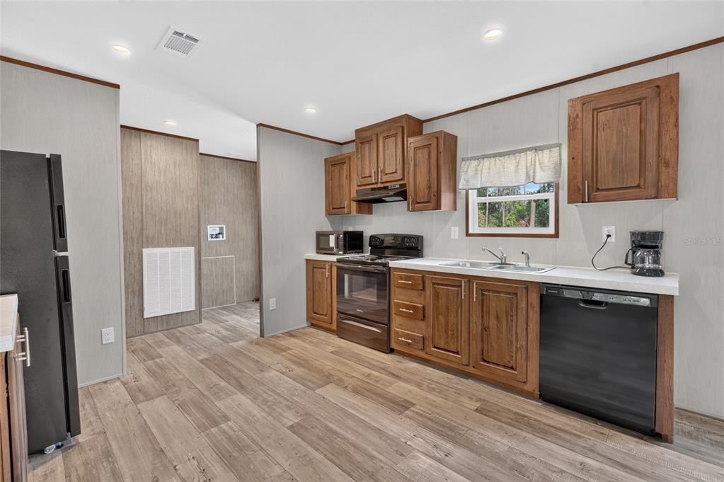 A kitchen features wood cabinets, a black refrigerator, a double sink, and wood-look flooring — 5759 SE 184 TERRACE, OCKLAWAHA, FL