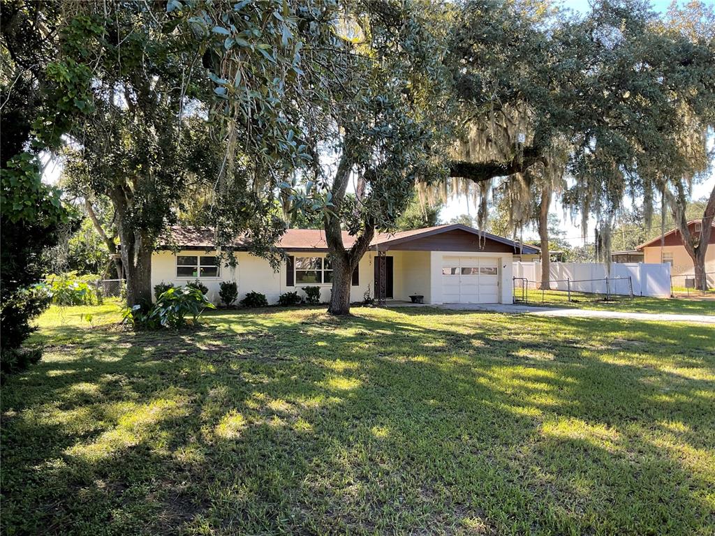 A single-story house with a white exterior, a garage, and large trees in the yard — 5032 FLAMINGO LANE, DADE CITY, FL