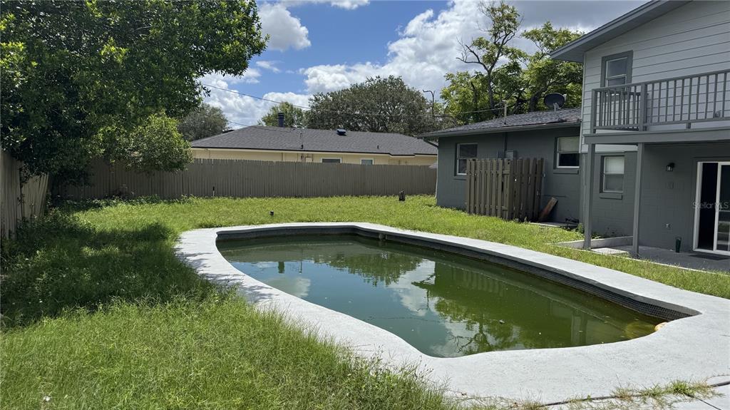 A backyard features a green, unmaintained swimming pool and a two-story gray house — 2189 SUSSEX ROAD, WINTER PARK, FL