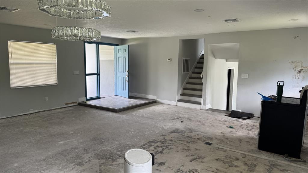 An unfinished living area features a raised entryway, a blue front door, and a staircase — 2189 SUSSEX ROAD, WINTER PARK, FL