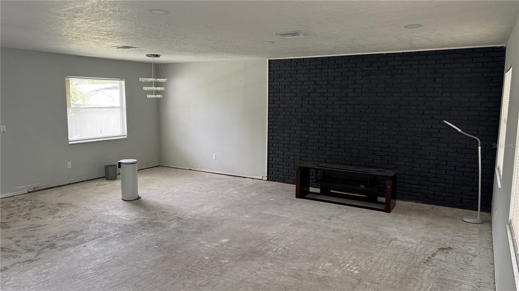 An unfurnished room features light gray walls, a black brick accent wall, and concrete flooring — 2189 SUSSEX ROAD, WINTER PARK, FL