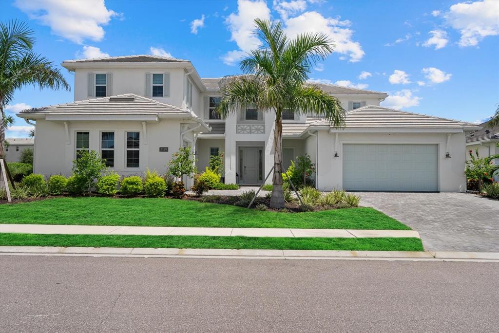 A two-story suburban house with a light-colored exterior, a tile roof, and a paved driveway — 8129 NEVIS RUN, LAKEWOOD RANCH, FL