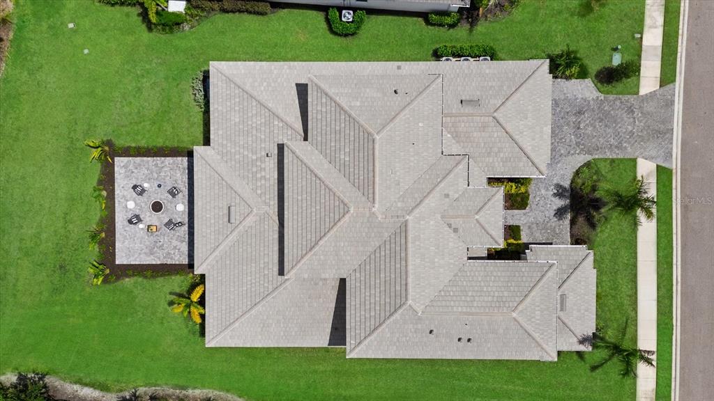 An aerial view shows a house with a tiled roof, a patio, and a driveway — 8129 NEVIS RUN, LAKEWOOD RANCH, FL