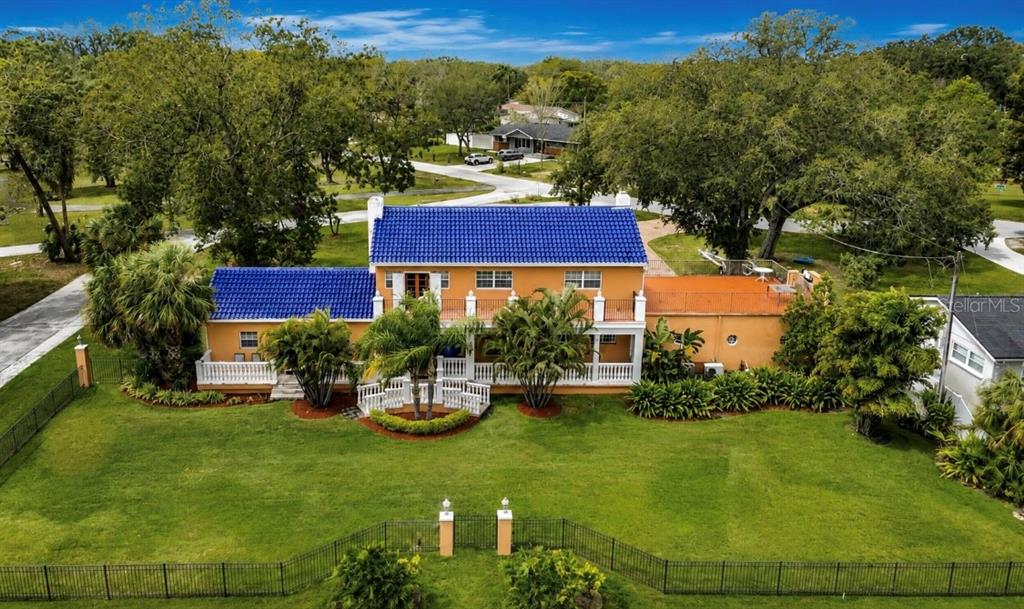 An aerial view of a two-story house with a blue tile roof and orange stucco exterior — 4929 N RIVER SHORE DRIVE, TAMPA, FL