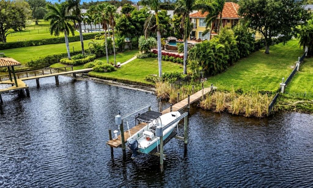 An aerial view of a waterfront property featuring a boat lift, dock, and landscaped yard — 4929 N RIVER SHORE DRIVE, TAMPA, FL