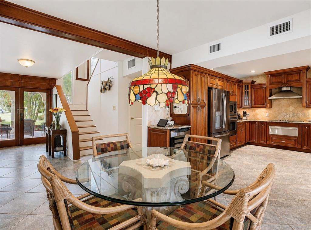 A dining area with a glass table, wicker chairs, and a stained-glass lamp near stairs — 4929 N RIVER SHORE DRIVE, TAMPA, FL