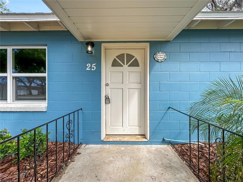 The exterior of a blue concrete block house features a white front door and railings — 25 E CHARLOTTE AVENUE, EUSTIS, FL