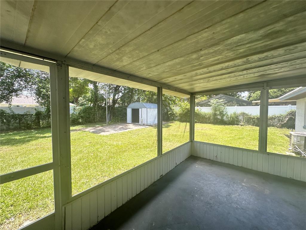A screened-in porch overlooks a grassy backyard with a small metal storage shed — 5078 SE 135TH STREET, SUMMERFIELD, FL