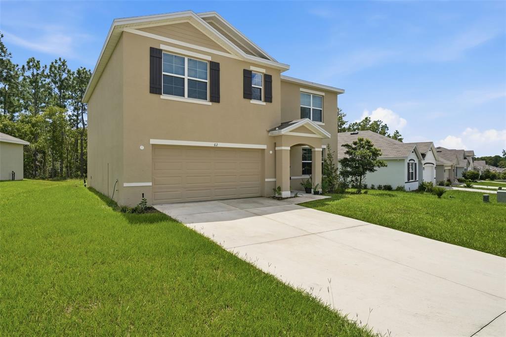A two-story tan house with a two-car garage and a concrete driveway — 62 HICKORY COURSE CIRCLE, OCALA, FL