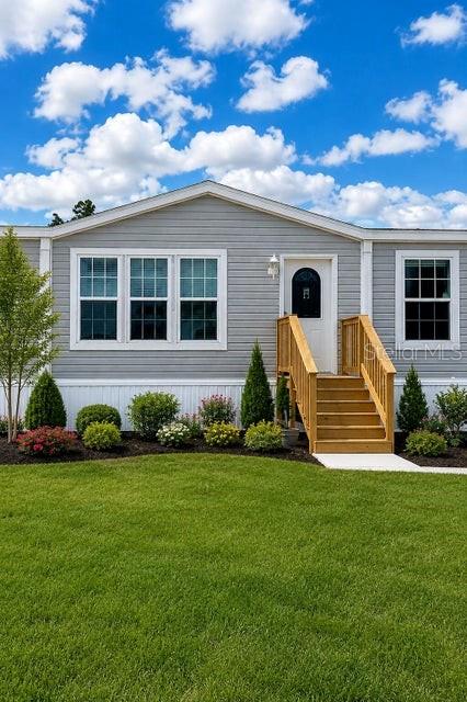 A gray manufactured home features a wooden staircase leading to the front entrance — 15136 NW 292ND STREET, OKEECHOBEE, FL