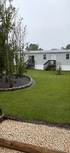 A view of a manufactured home exterior with a lawn, landscaping, and two wooden decks — 15136 NW 292ND STREET, OKEECHOBEE, FL