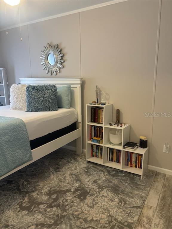 A bedroom features a white bed, a stepped white bookshelf, and a gray patterned rug — 15136 NW 292ND STREET, OKEECHOBEE, FL